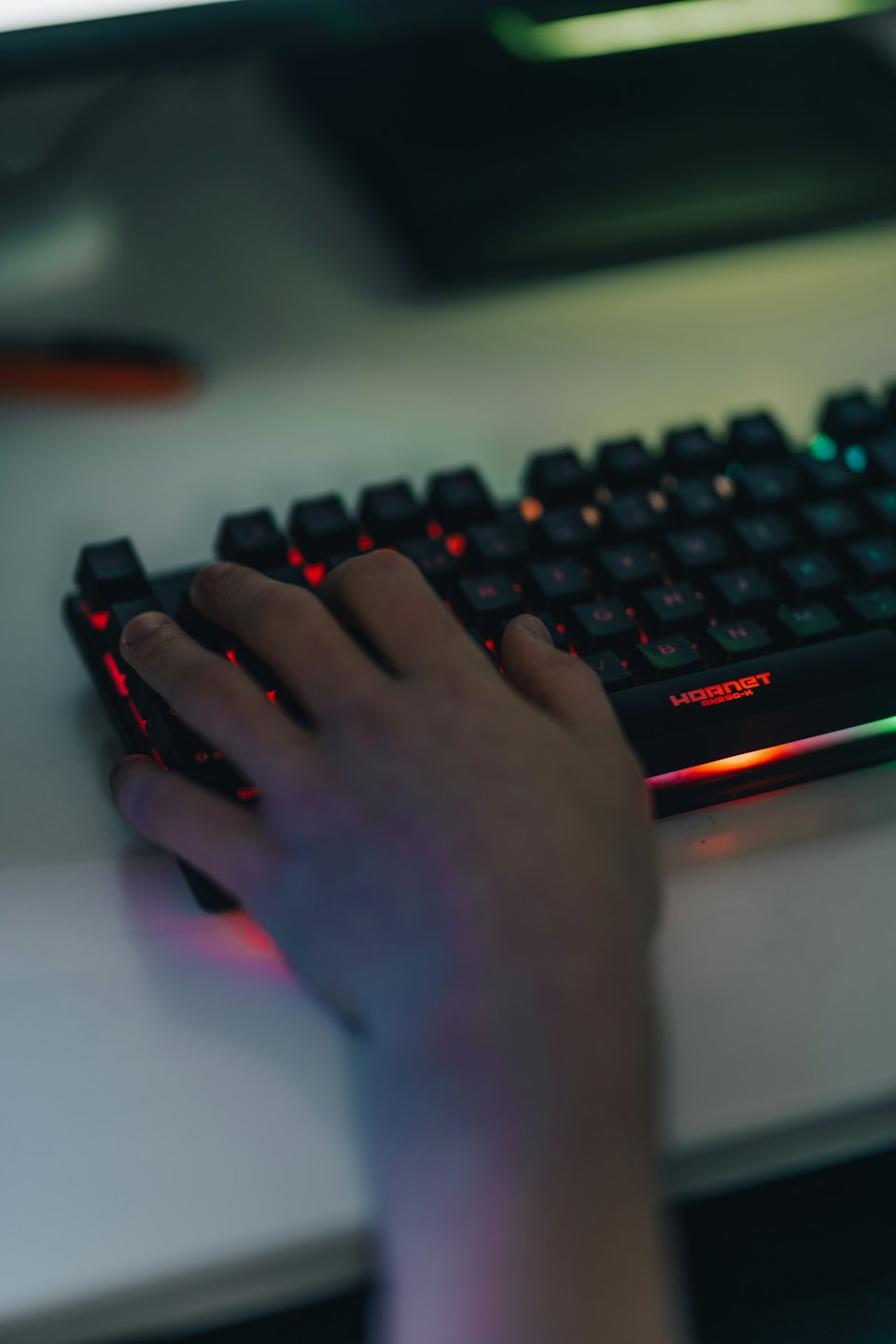 A hand typing on a glowing mechanical keyboard.