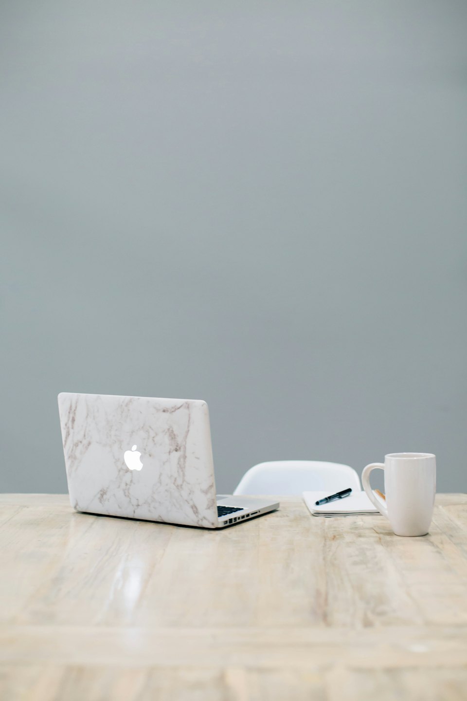 Laptop, notebook, and coffee mug on a wooden desk.